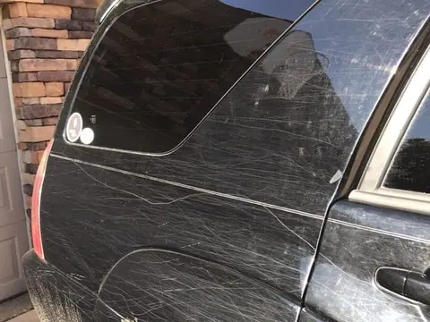 Heavily scratched and dull black paint before correction